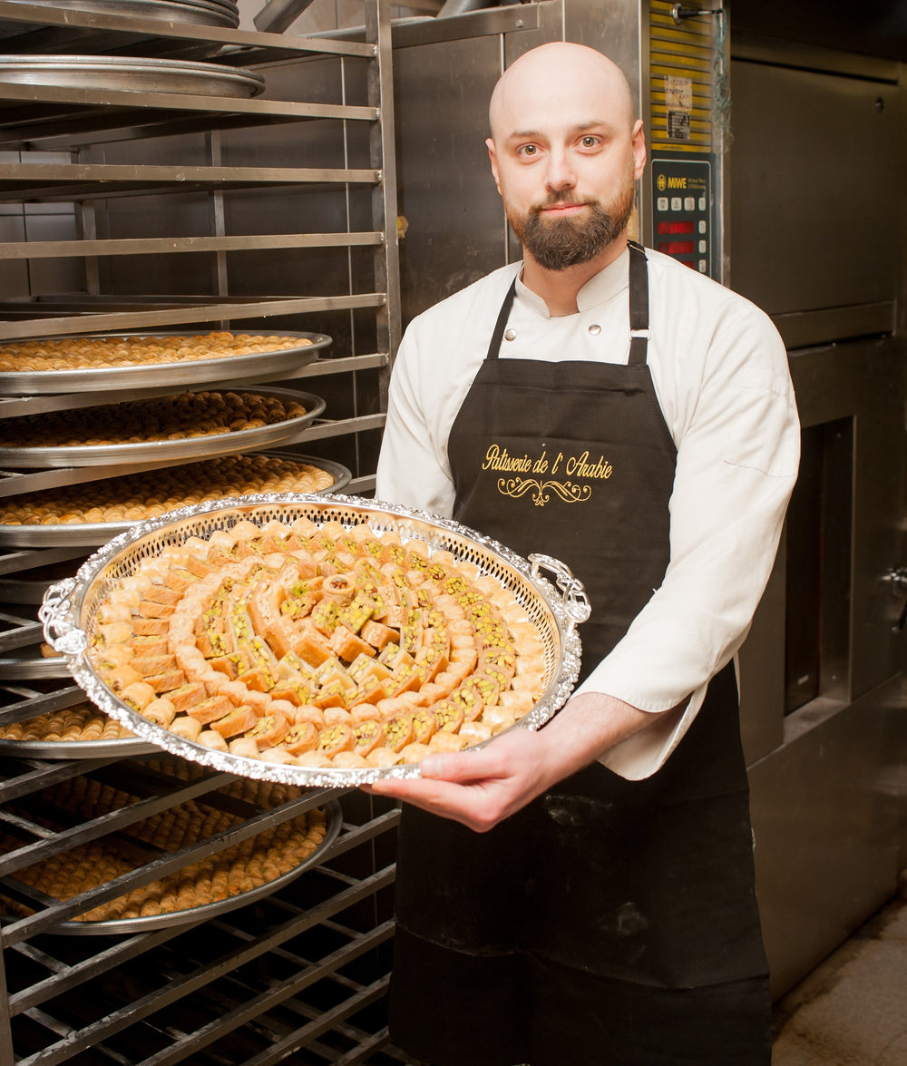 Konditor der Patisserie de l'Arabie mit frisch gebackenem Baklava-Blech in der Produktion
